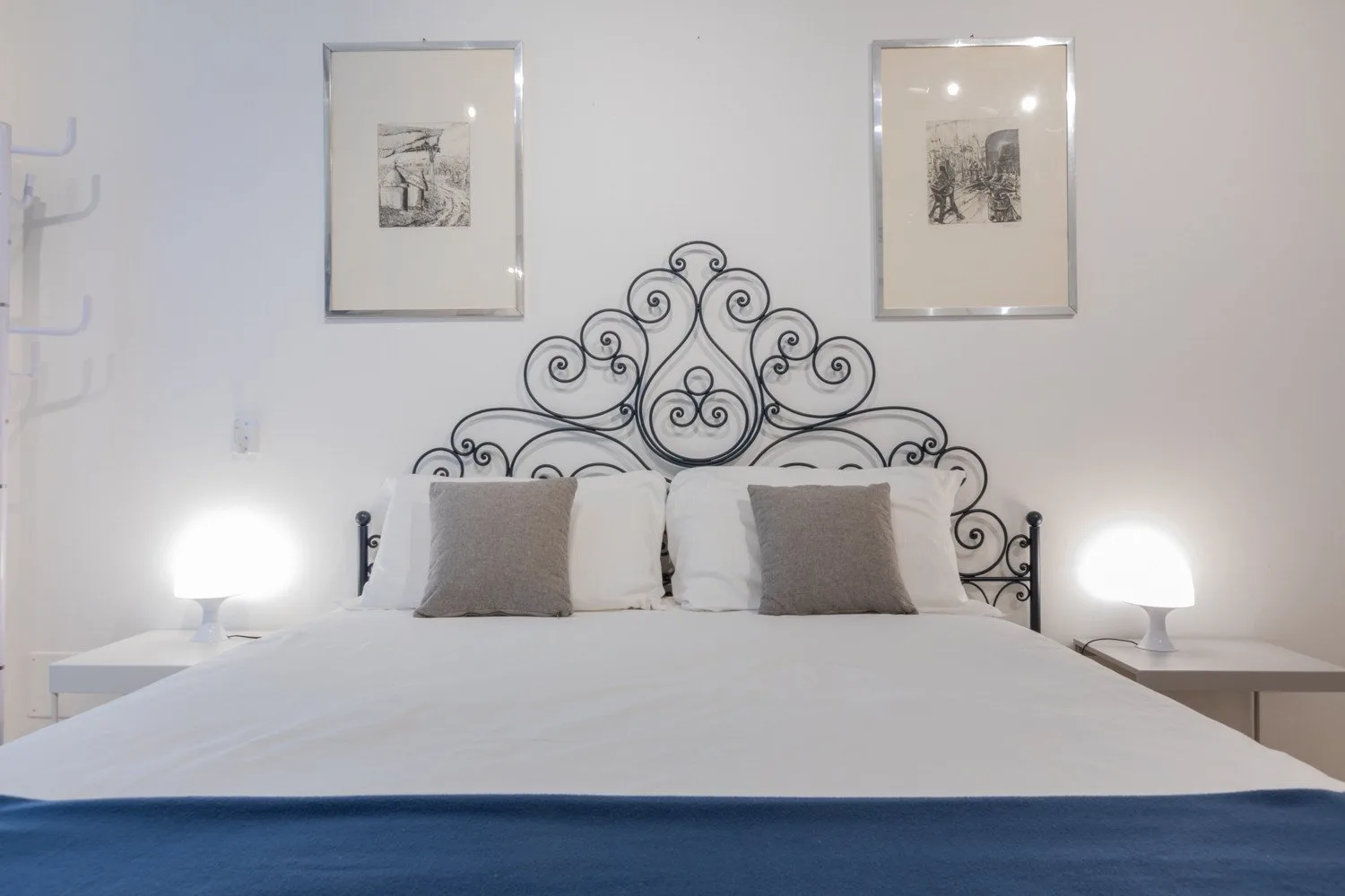 Un dormitorio con una cama, un cabecero decorativo de metal y lámparas de mesilla.