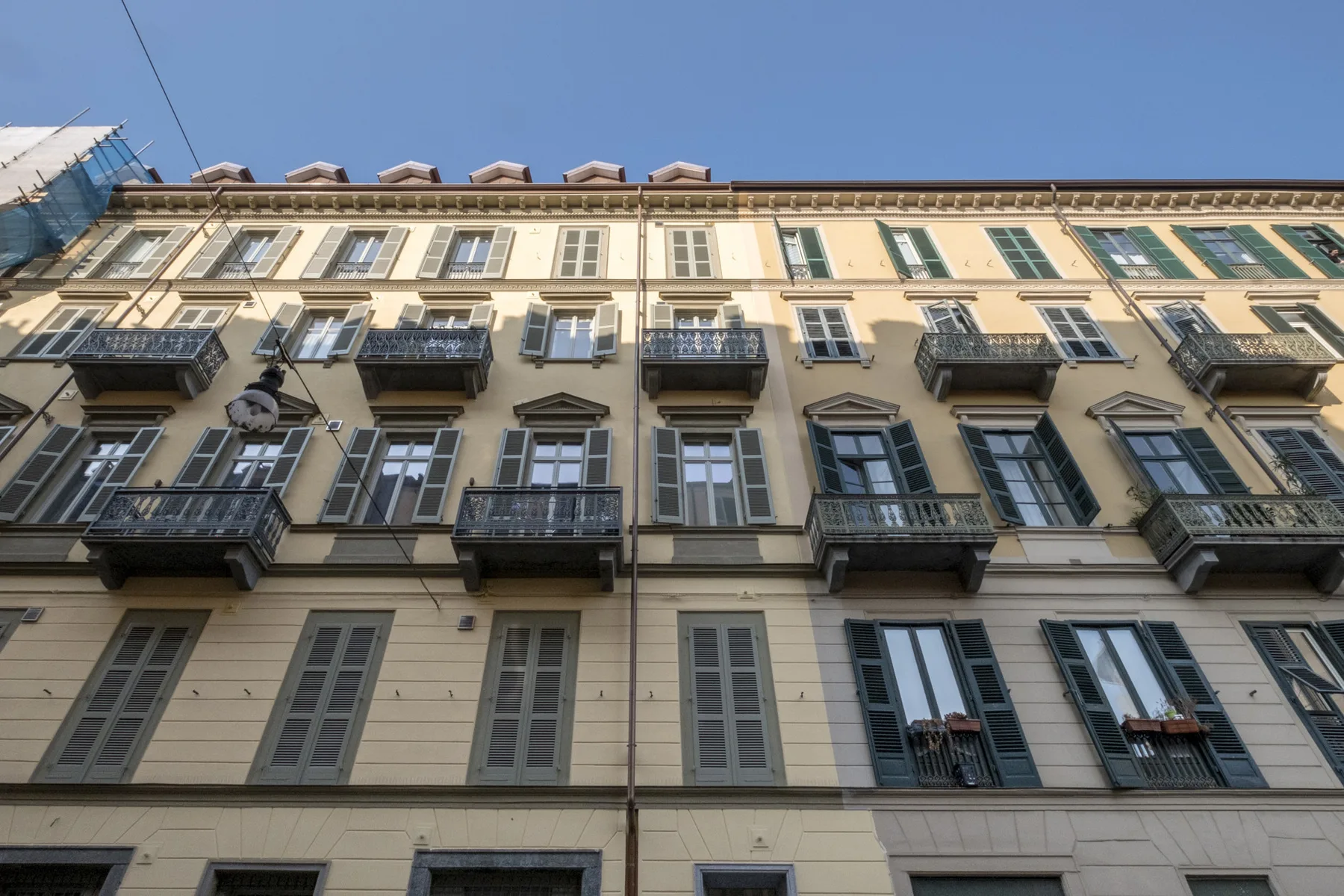 La fachada de un edificio de varias plantas con filas de ventanas y pequeños balcones bajo un cielo despejado.