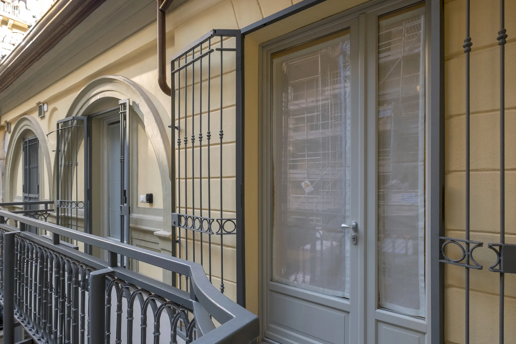 Un pasillo exterior con barandillas y una puerta acristalada.