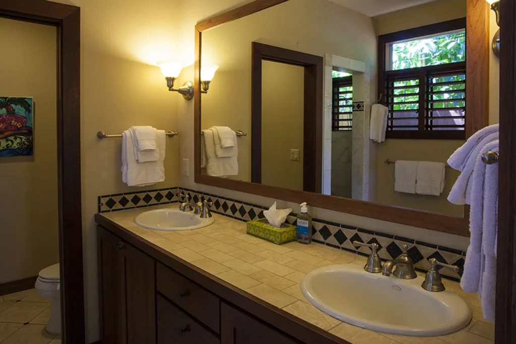 A bathroom vanity with two sinks, a large mirror, and towels.