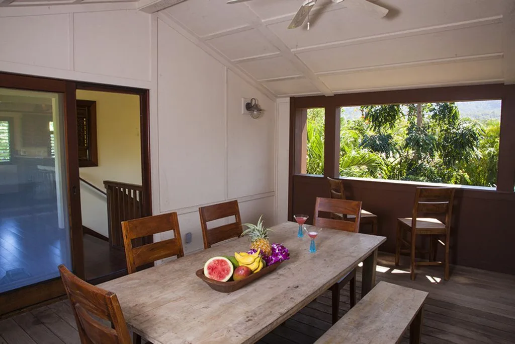 A dining area with a table, wooden seating, and a large window overlooking greenery.