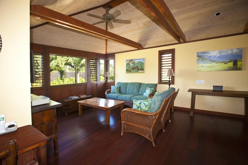 A living room with seating around a wooden coffee table and large windows.