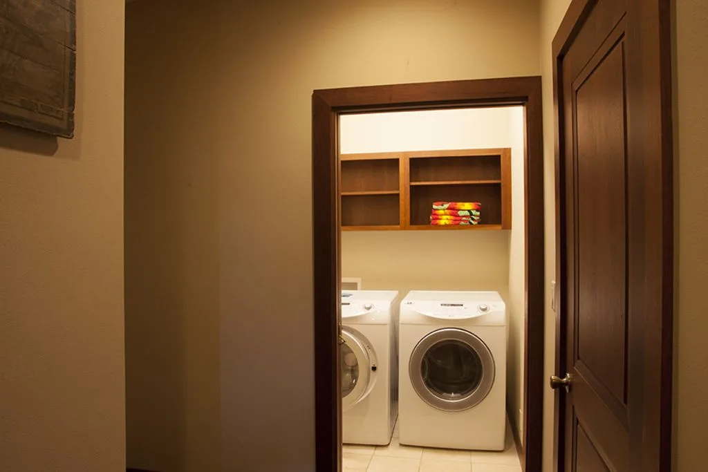 A laundry area with two front-loading machines and open shelves.