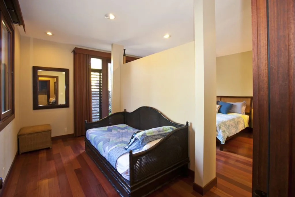 A bedroom with a dark wooden bed, patterned bedding, and a curtained window.