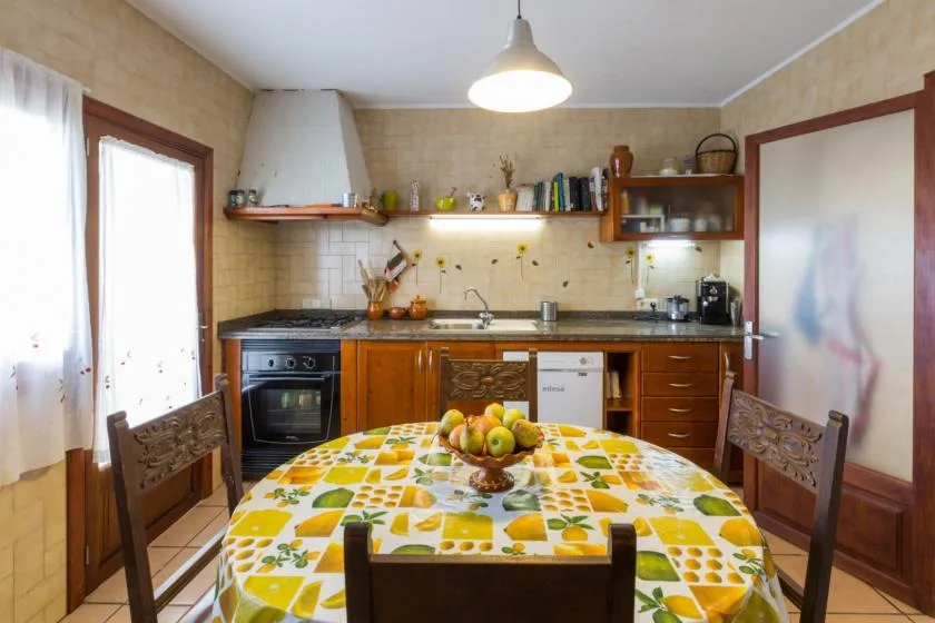 A kitchen and dining area with a fruit-covered table in the foreground.