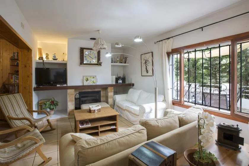 A living room with seating, a fireplace, and large windows overlooking greenery.