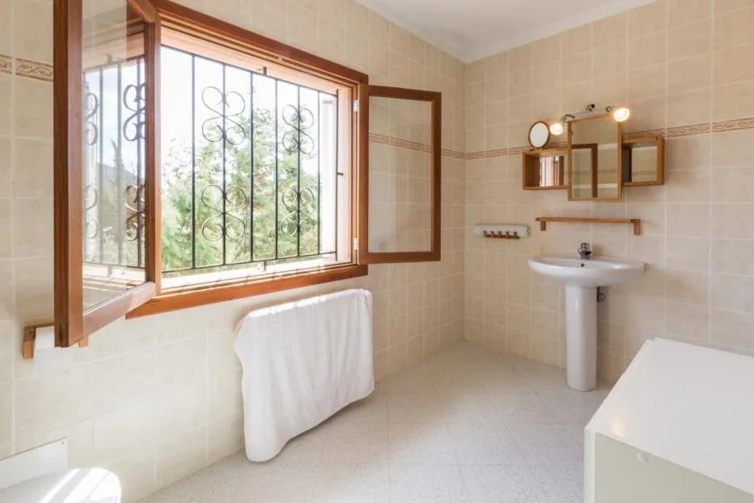 A tiled bathroom with a sink and a large window.