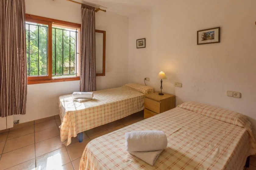 A bedroom with two single beds, a bedside table, and a window.