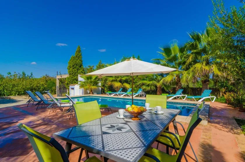 An outdoor poolside dining area with a table and chairs beside the pool.