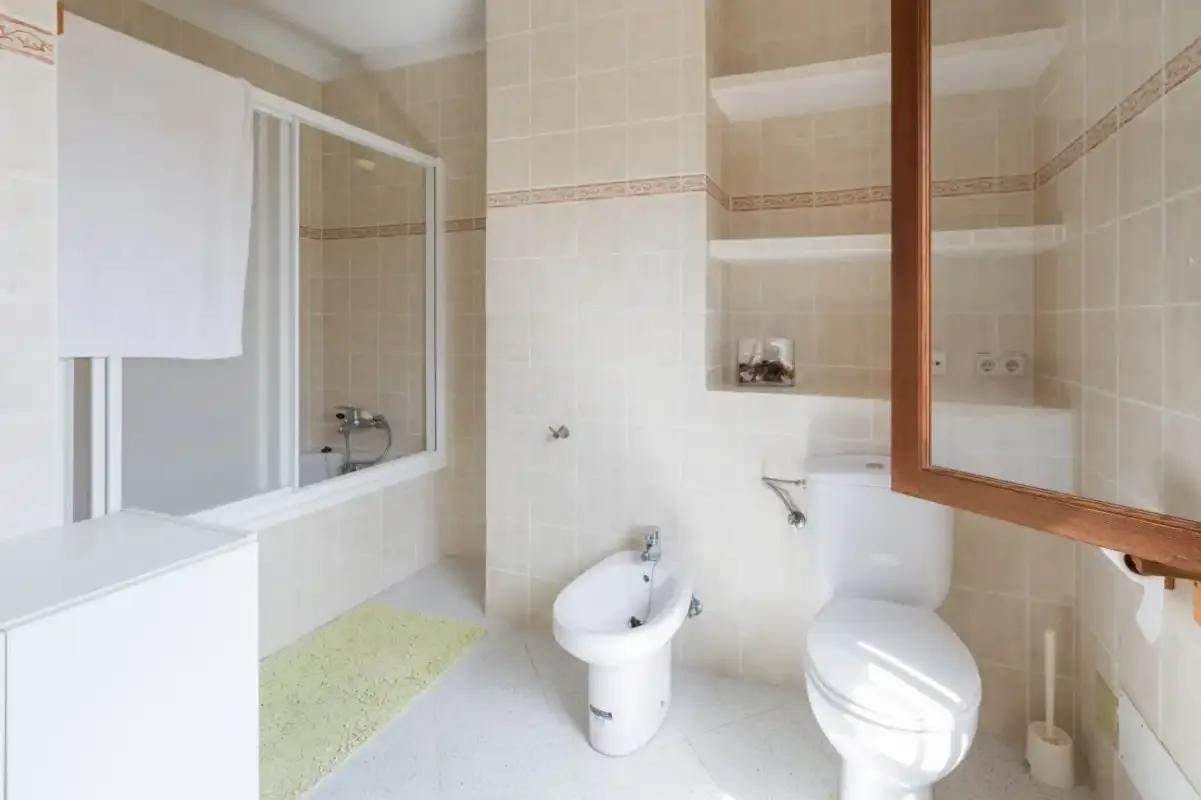 A tiled bathroom with a bathtub, toilet, and bidet.