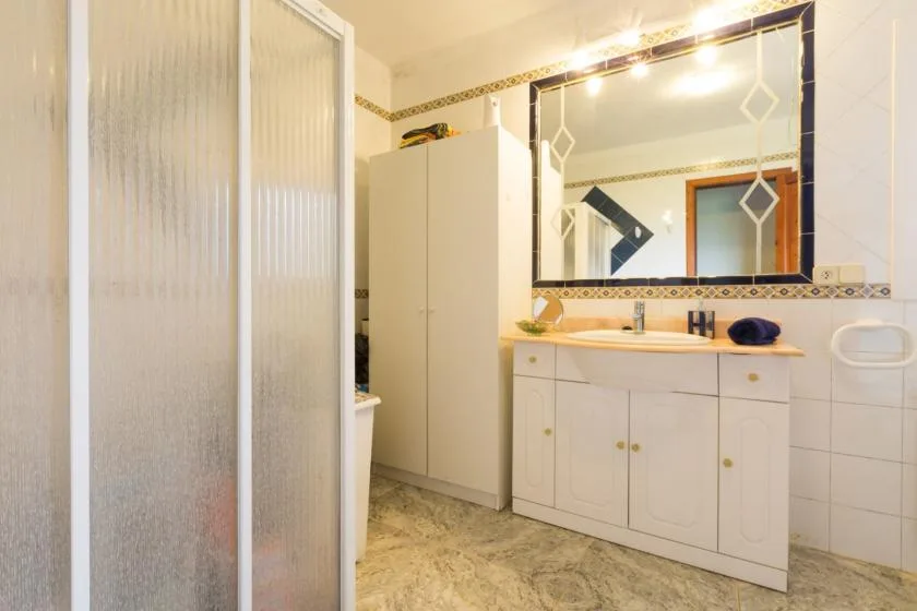 A bathroom with a large mirror above a long vanity.