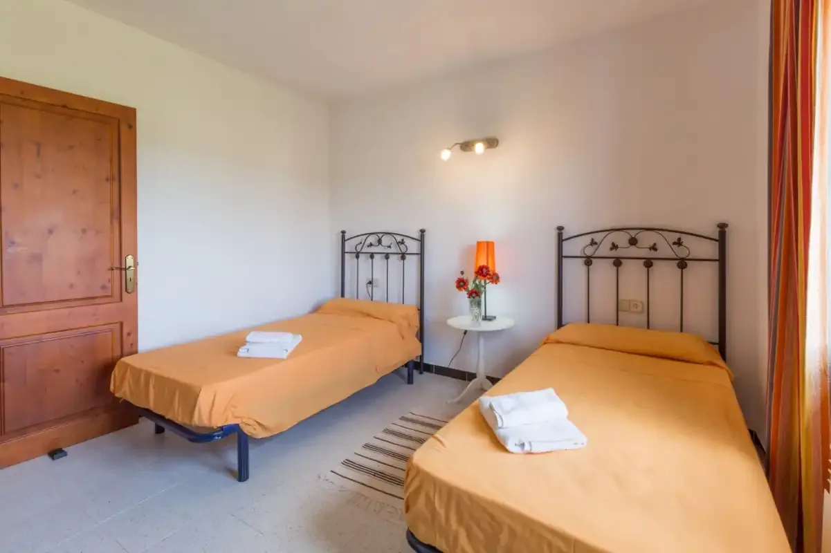 A bedroom with two single beds and a small table between them.
