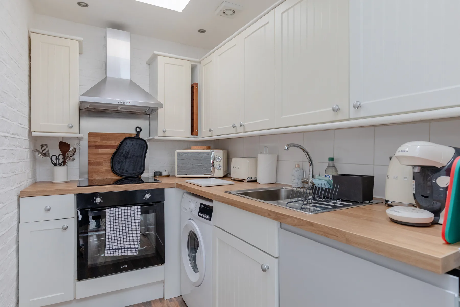 A compact kitchen with white cabinets, a countertop, and cooking appliances.