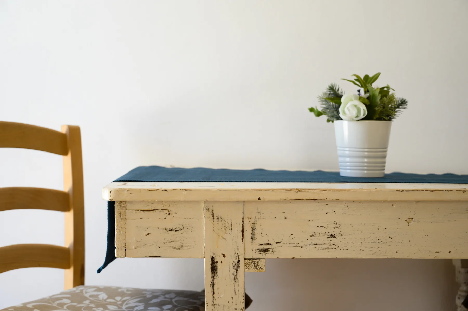 Un comedor con una mesa rústica, asientos de madera y una planta en maceta.