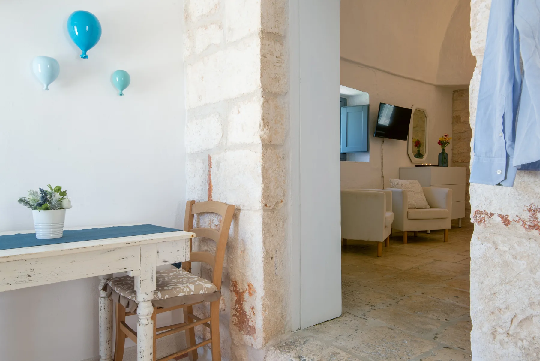 Un comedor luminoso se abre a una sala de estar con un sillón y un televisor.