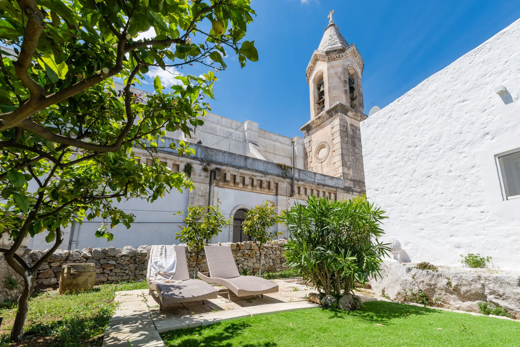 Un patio de piedra con asientos al aire libre y un alto campanario.