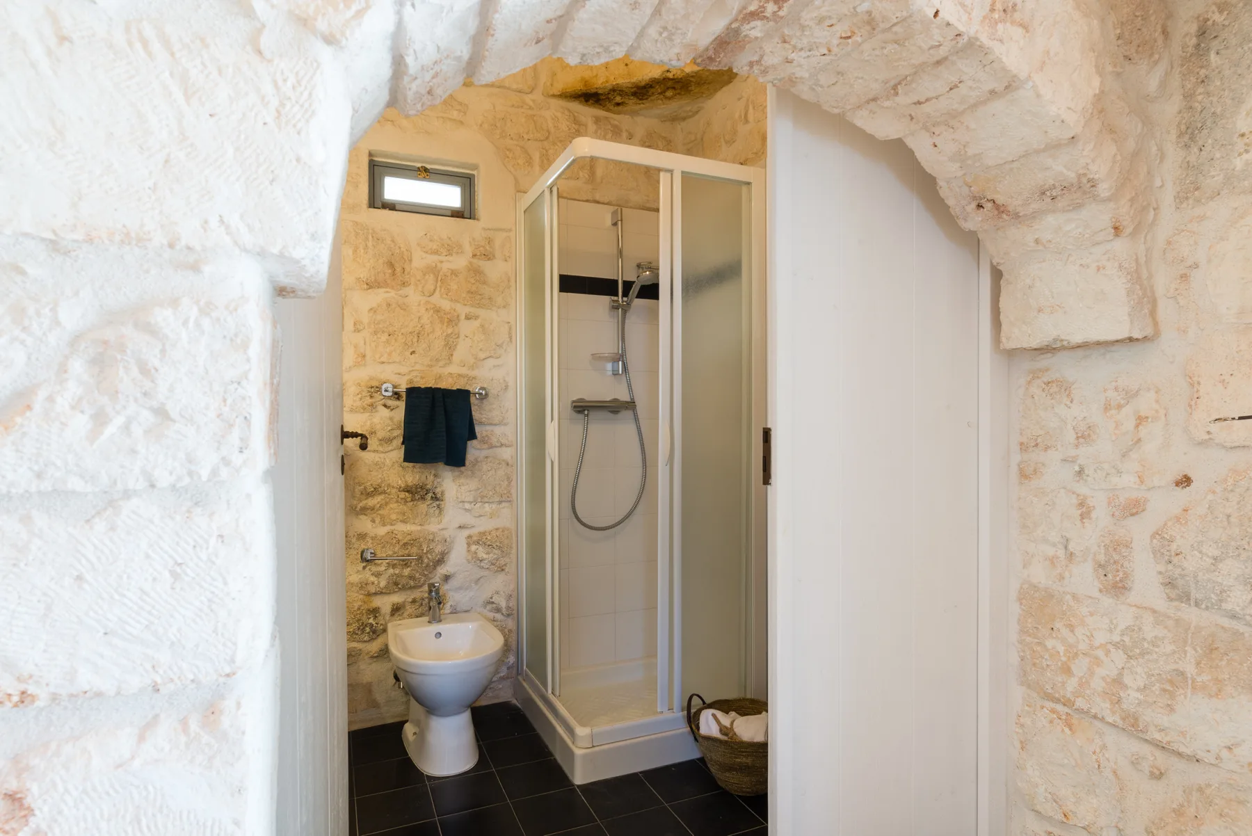 Un baño con una ducha de vidrio y paredes de piedra.