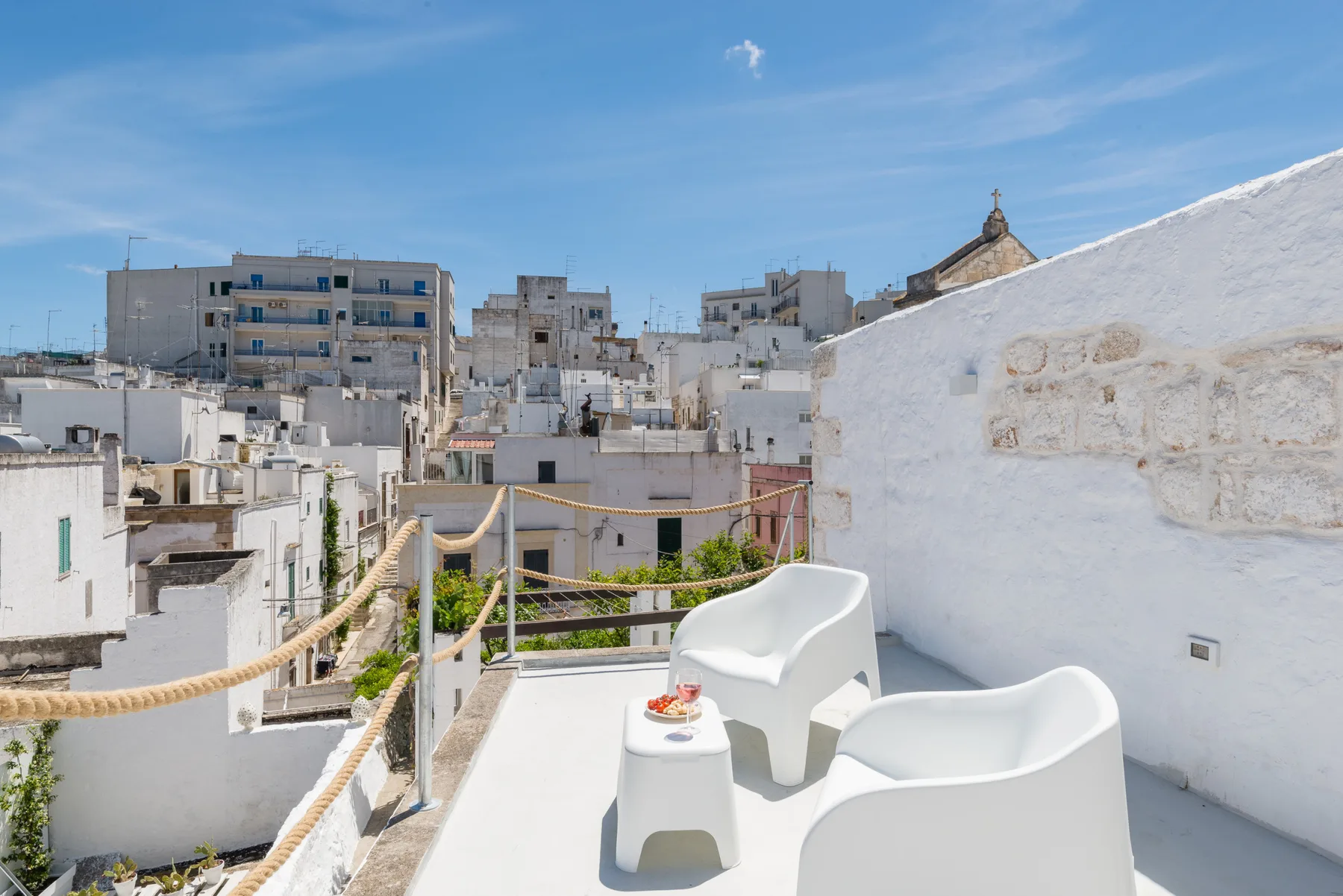 Una terraza blanca en la azotea ofrece vistas a edificios bajos bajo un cielo azul.