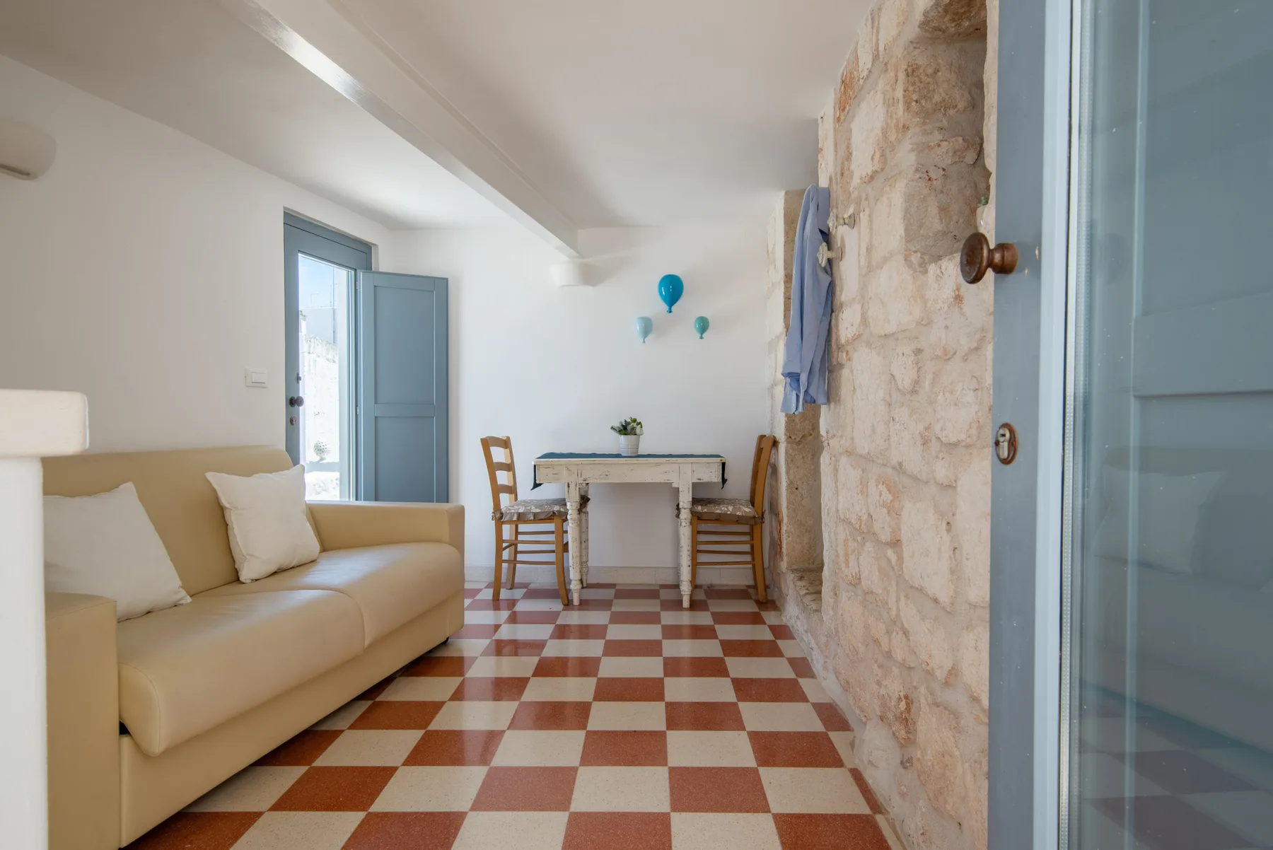 Un comedor y sala de estar luminosos con mesa, asientos y suelo a cuadros.