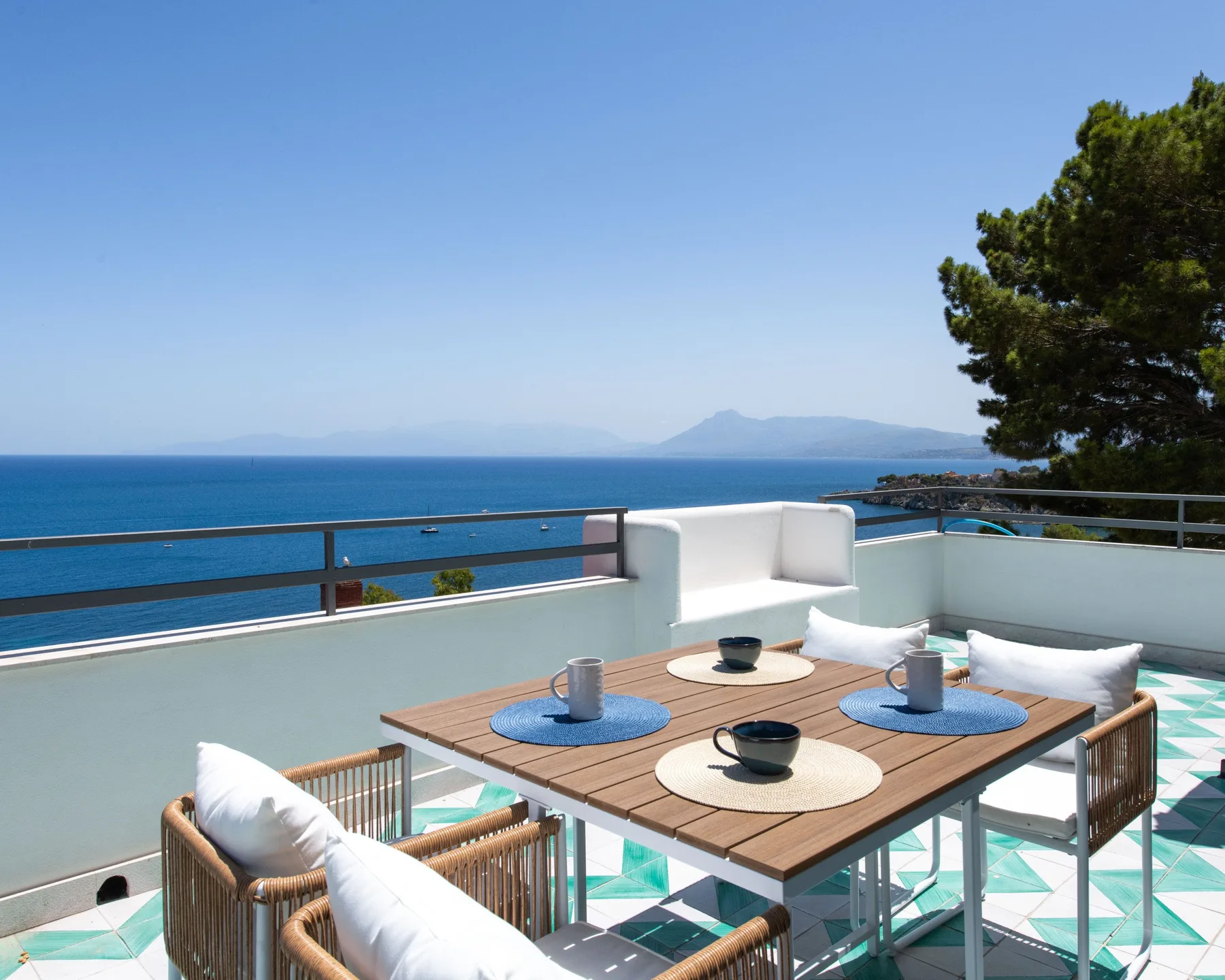 An outdoor terrace with a dining table and seating overlooking the sea.