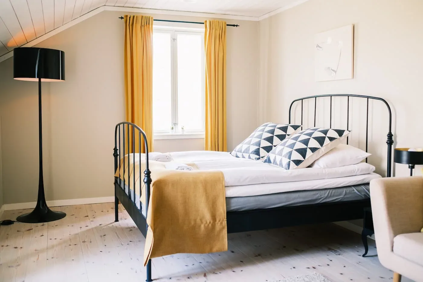 Habitación Klinga con una cama hecha y detalles amarillos.