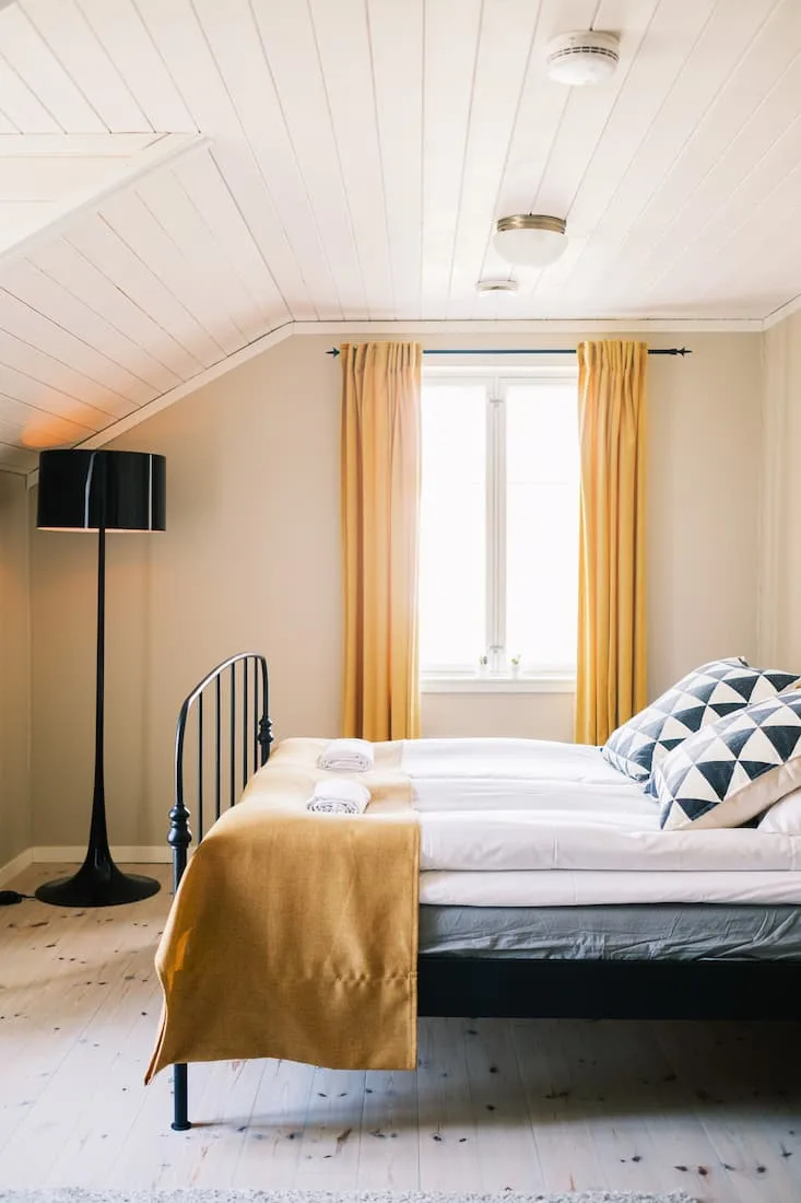 Habitación Klinga con una cama hecha y detalles amarillos.