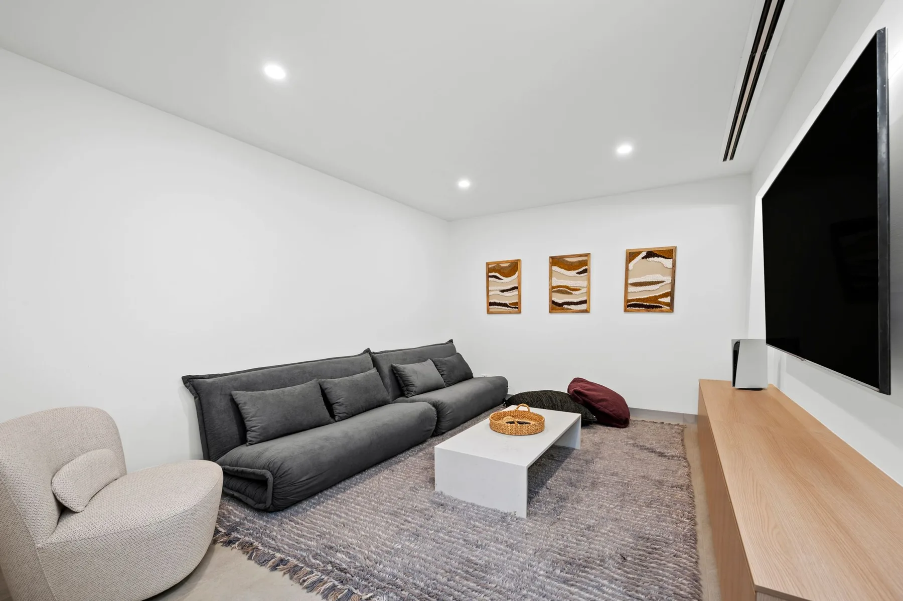 Una sala de estar moderna tiene un sofá gris, una mesa de centro y cuadros en la pared.