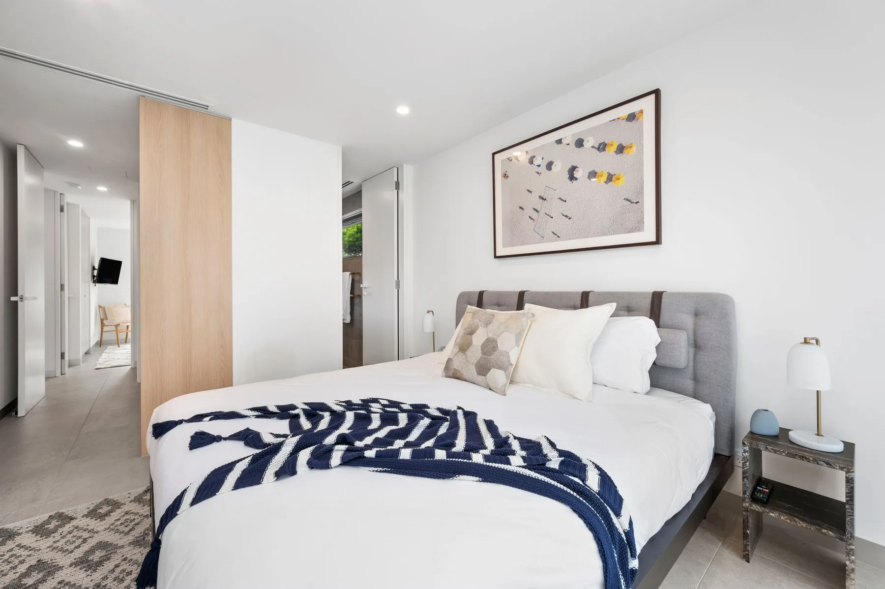Un dormitorio luminoso con una cama arreglada y un cuadro enmarcado sobre el cabecero.