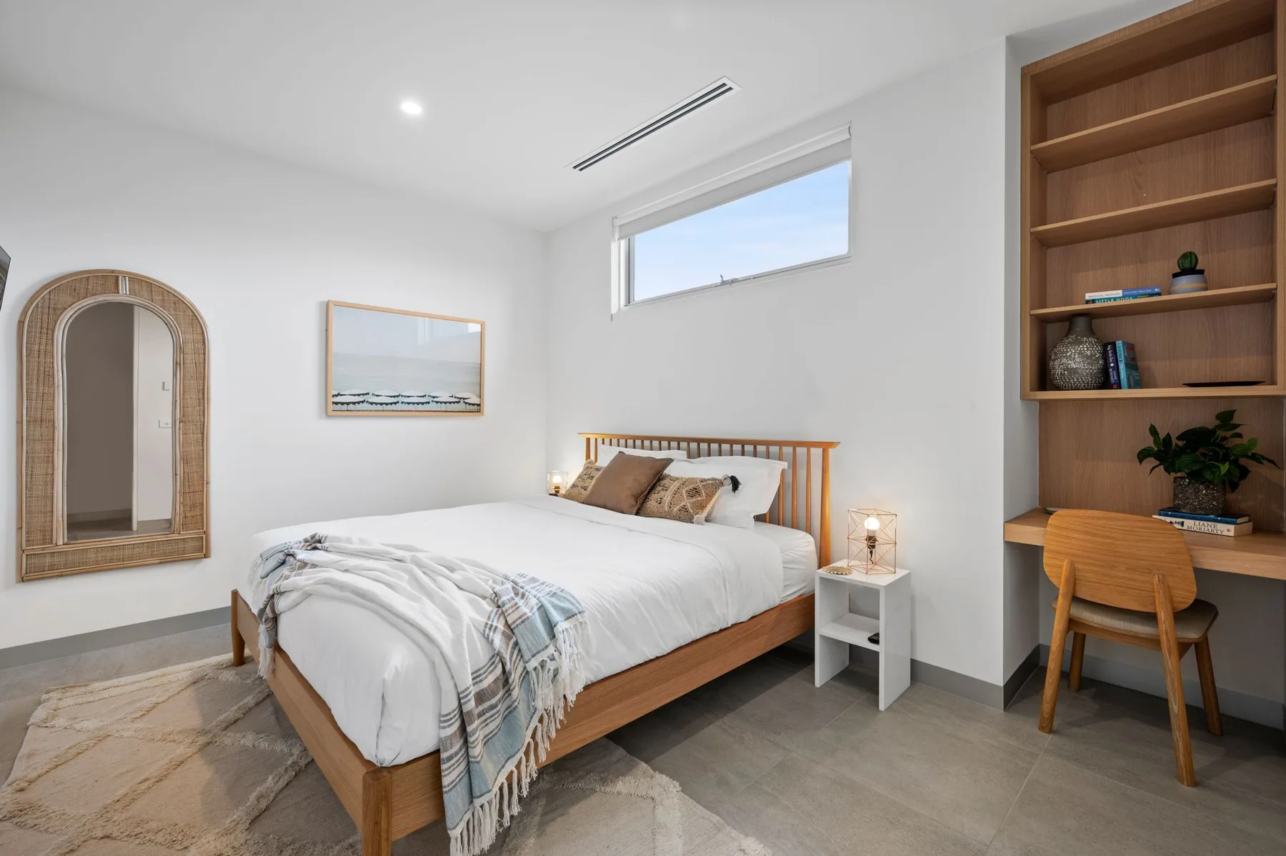 Un dormitorio luminoso con una cama de madera y un escritorio con estantes.