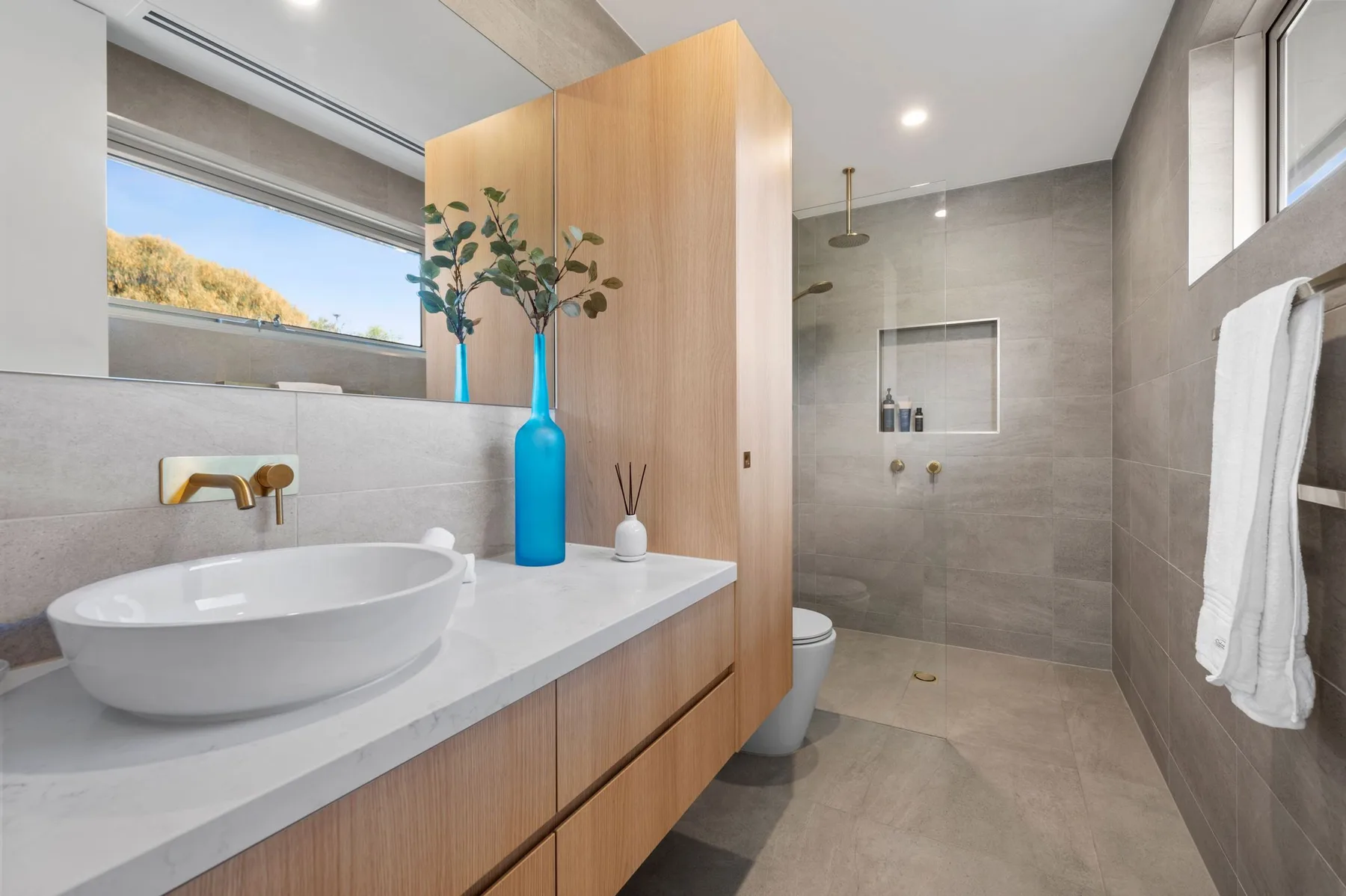 Un baño moderno con lavabo sobre encimera, mueble y ducha.