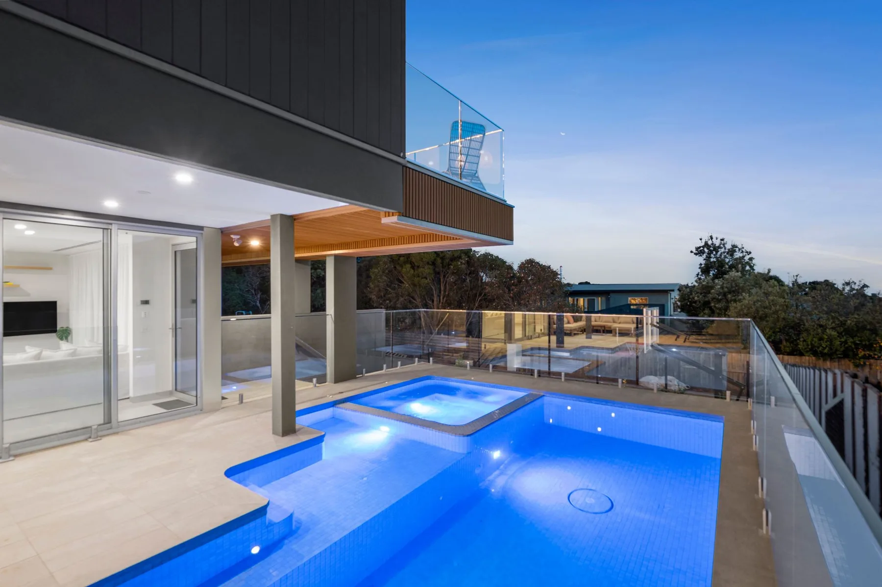 Una piscina exterior y un spa están junto a una casa moderna.
