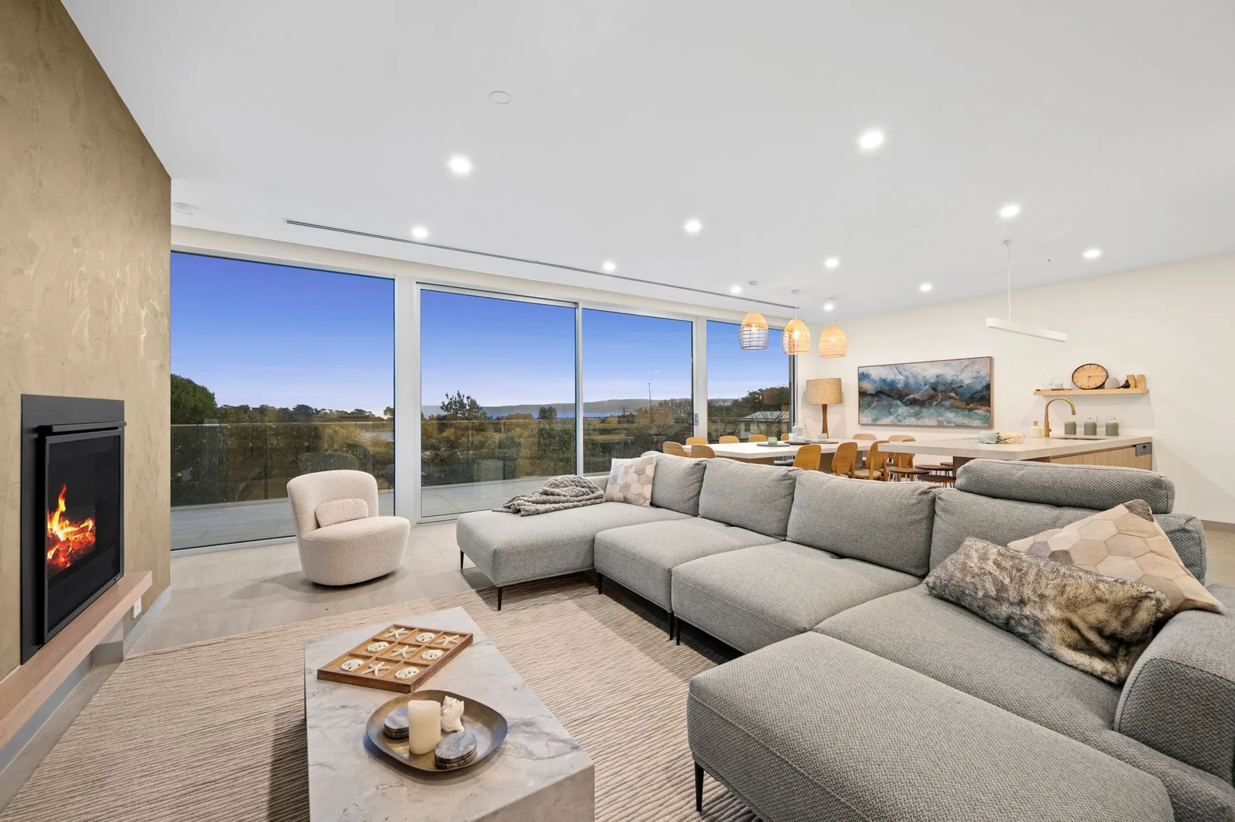 Una sala luminosa tiene grandes ventanales con vistas a un paisaje verde.