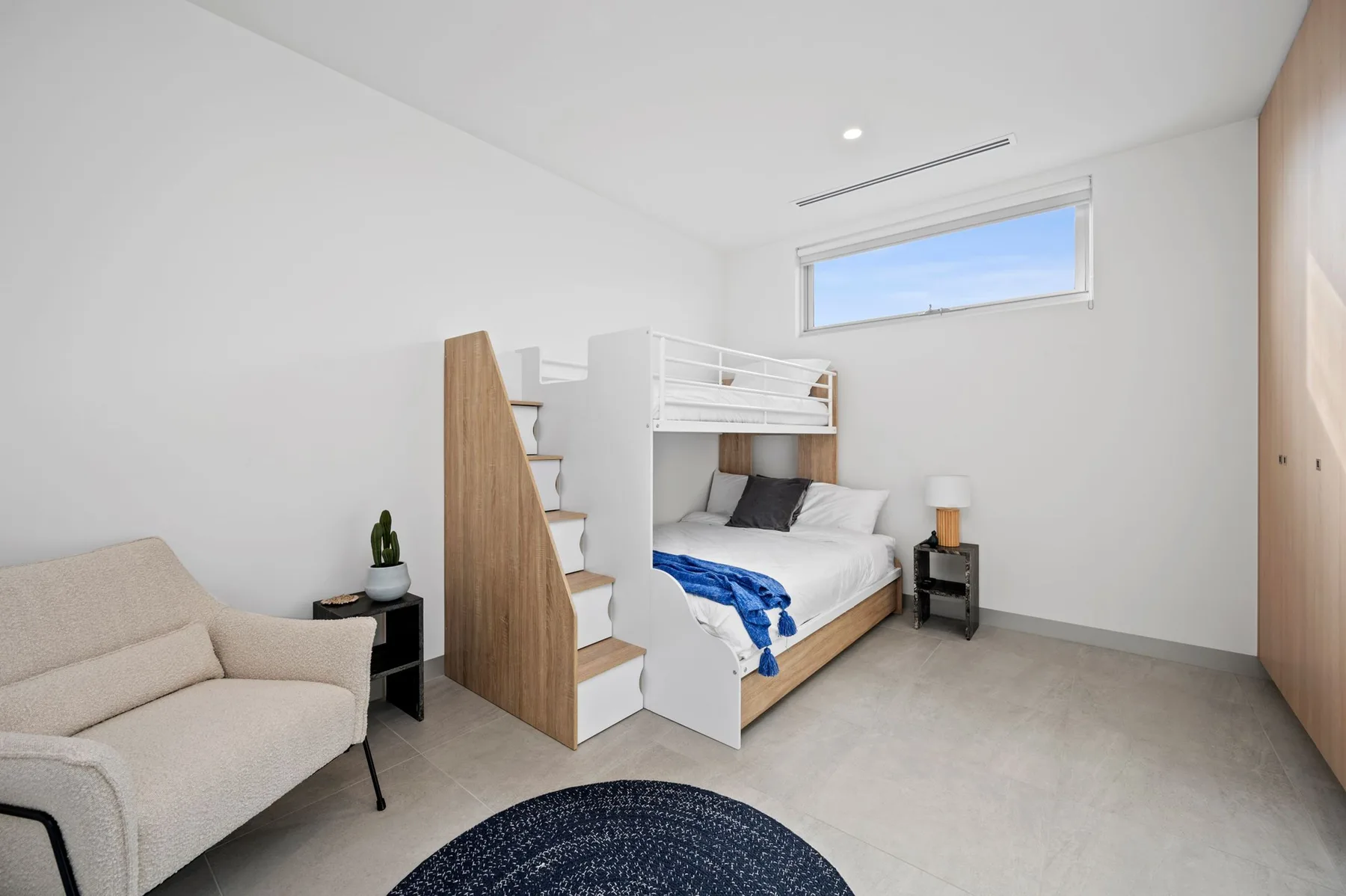 Un dormitorio luminoso tiene una cama con litera superior y una zona de estar.