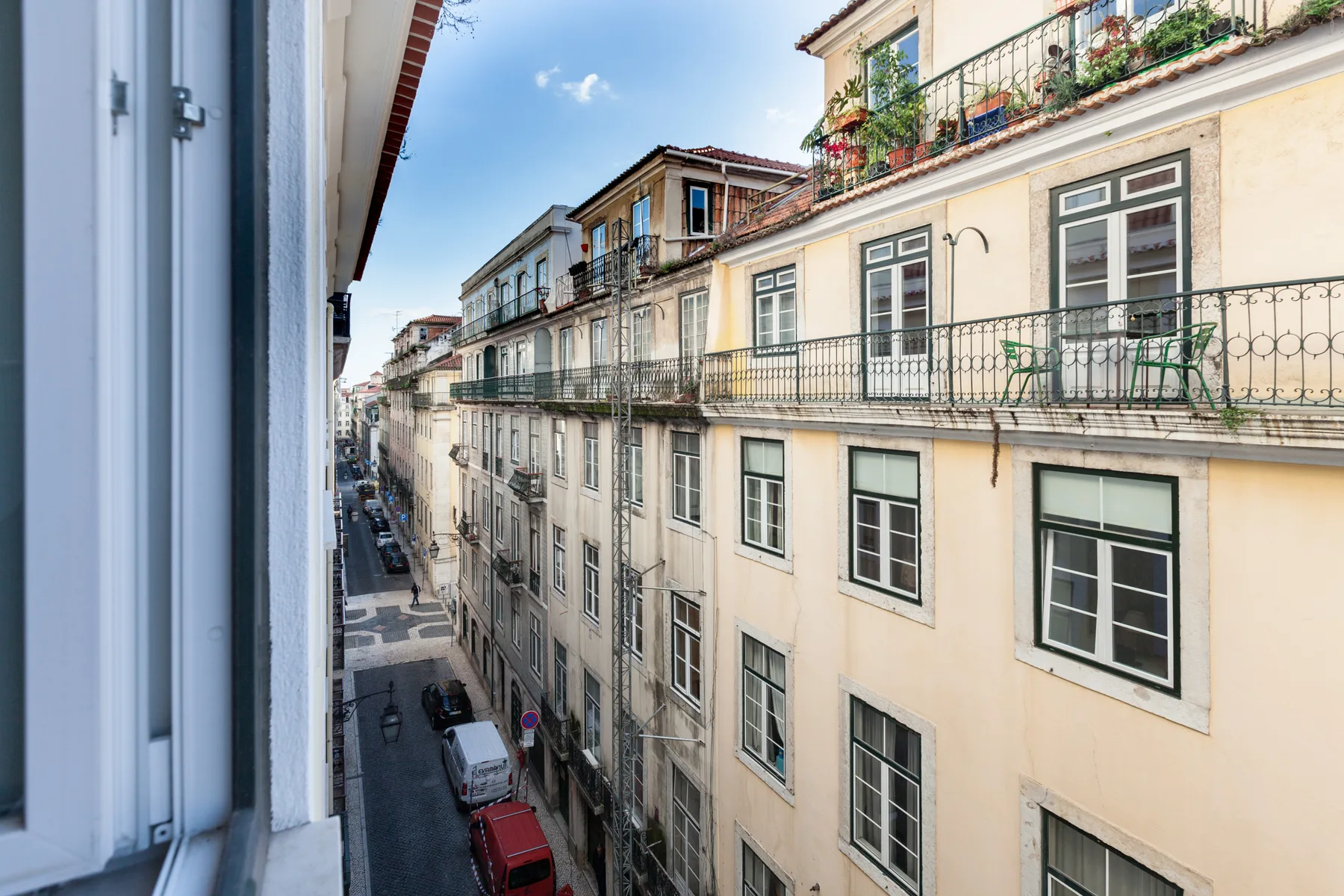 Una calle estrecha de la ciudad flanqueada por edificios de varias plantas y balcones.