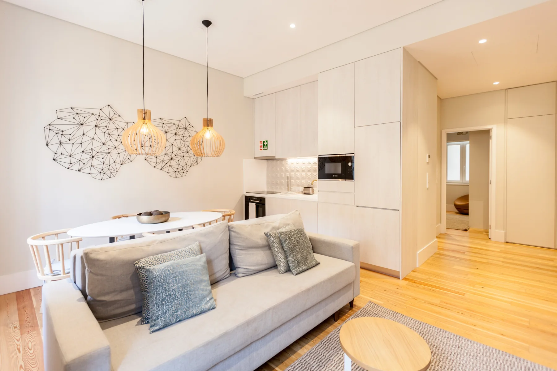 Una sala luminosa con asientos, una mesa de comedor y una cocina abierta.