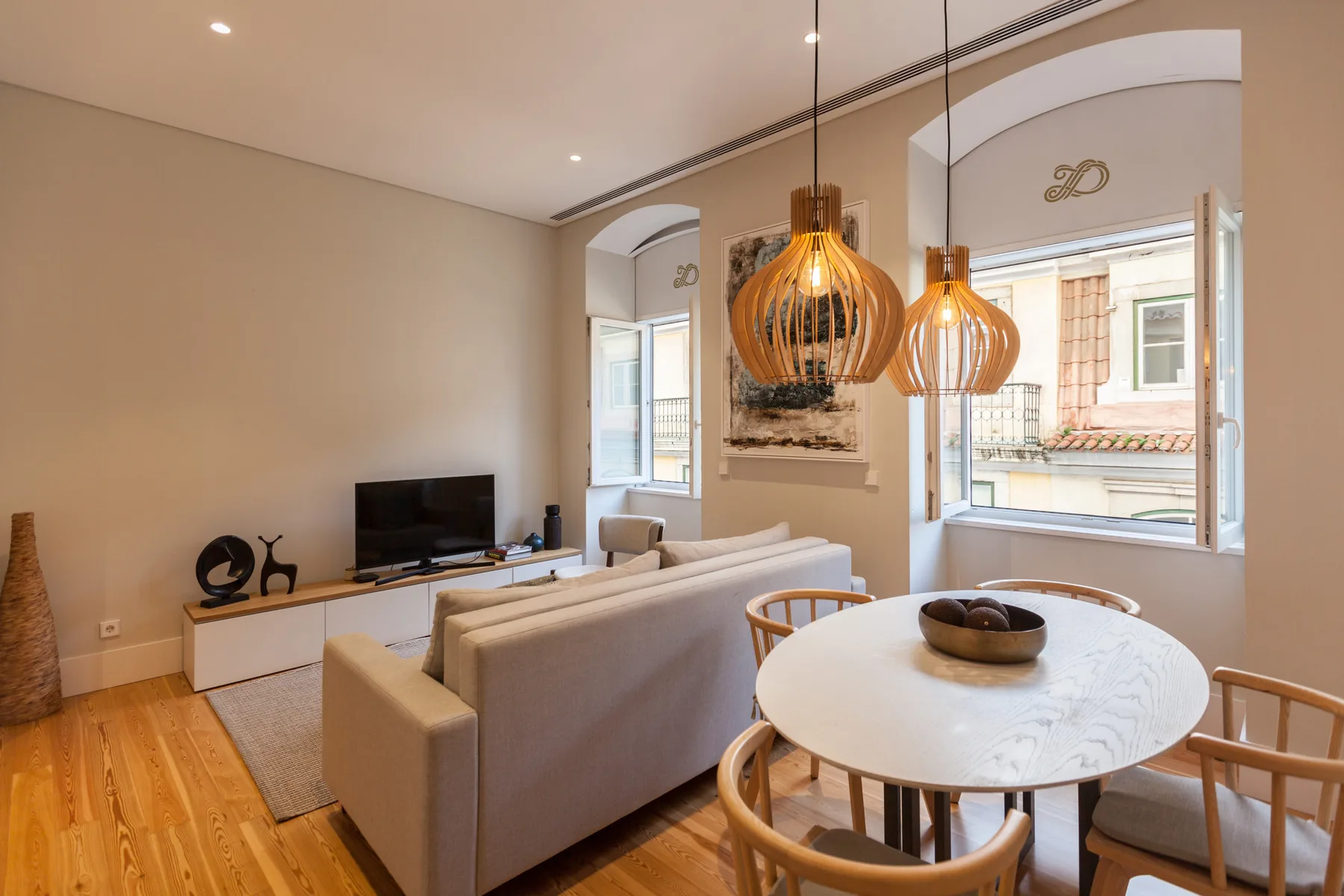 Una sala de estar y comedor con asientos, un televisor y ventanas amplias.