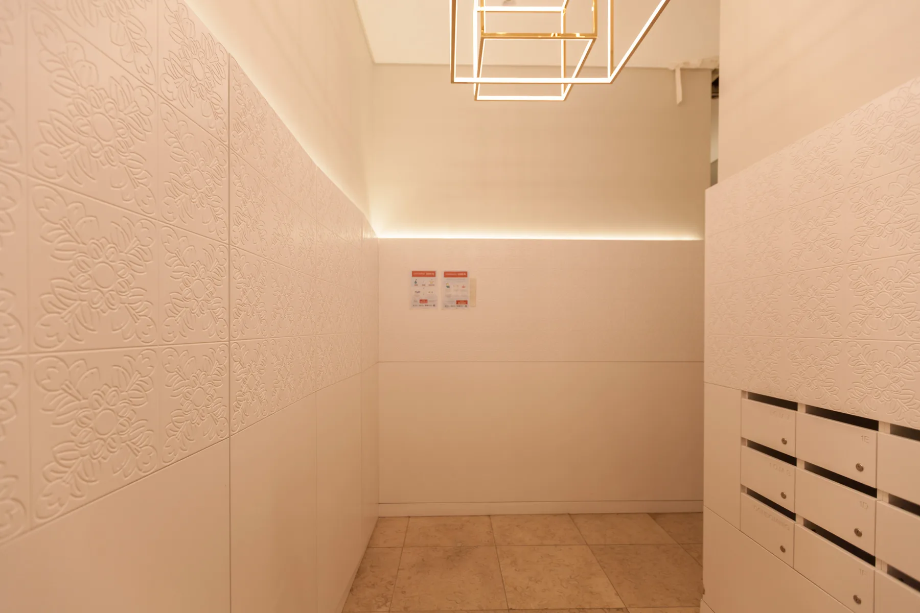 Pasillo de apartamento con paredes de azulejos y una fila de buzones.
