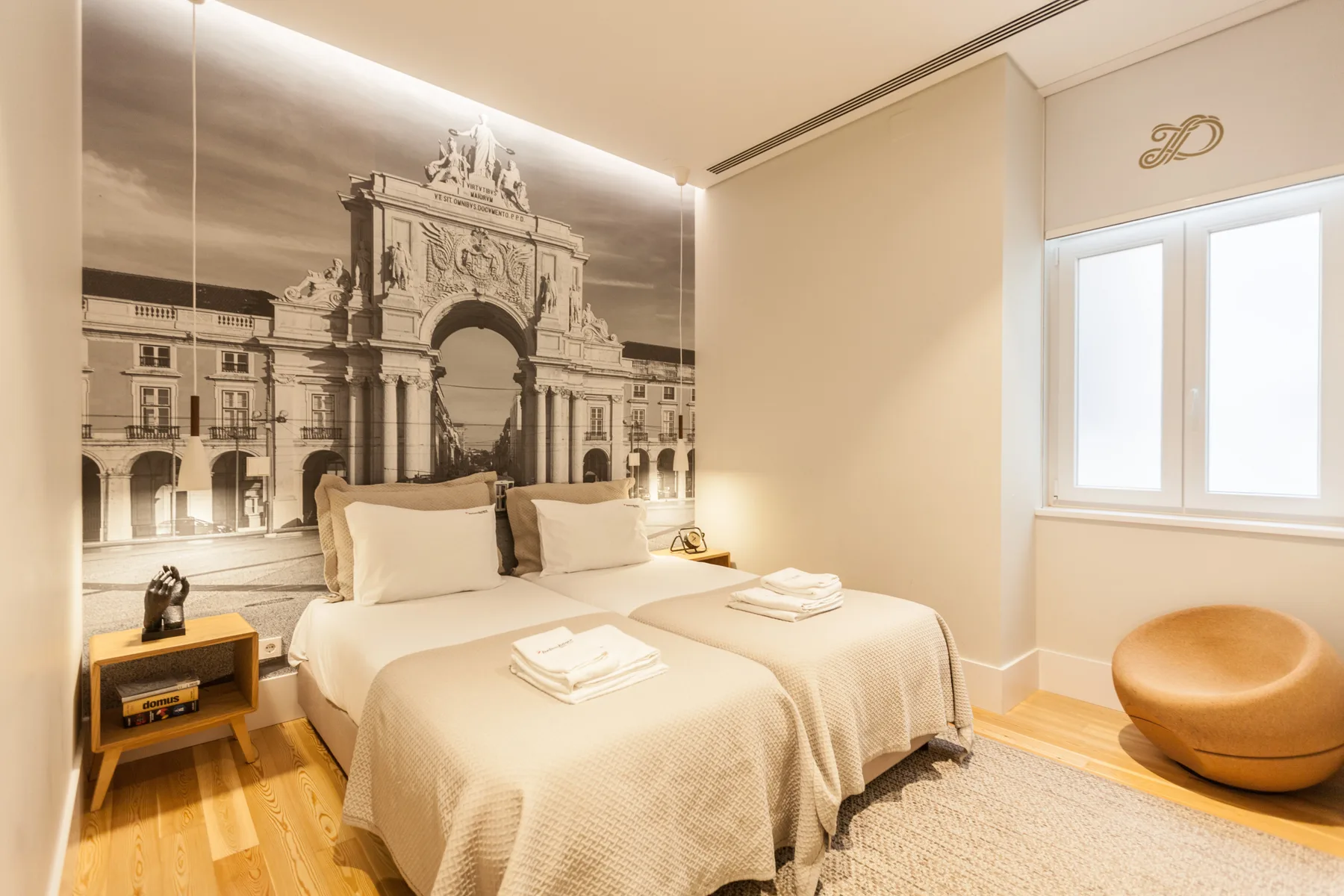 A bedroom with a bed beneath a large black-and-white architectural mural.