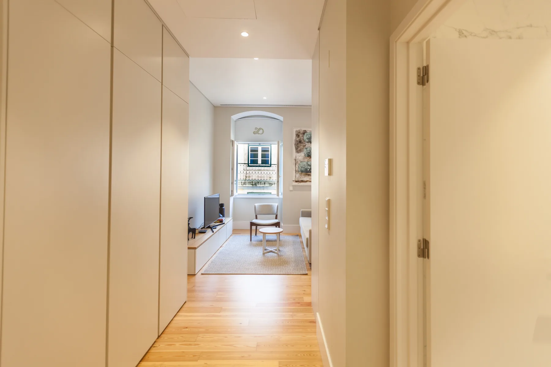 Un pasillo da a una sala luminosa con asientos y una ventana.