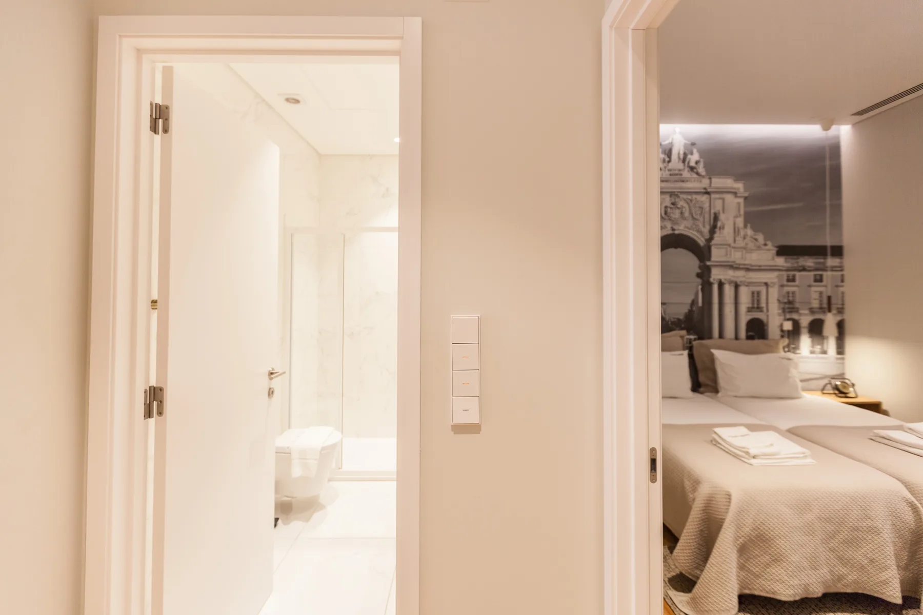 Se ve un dormitorio con una cama a través de una puerta abierta, junto a un baño luminoso.