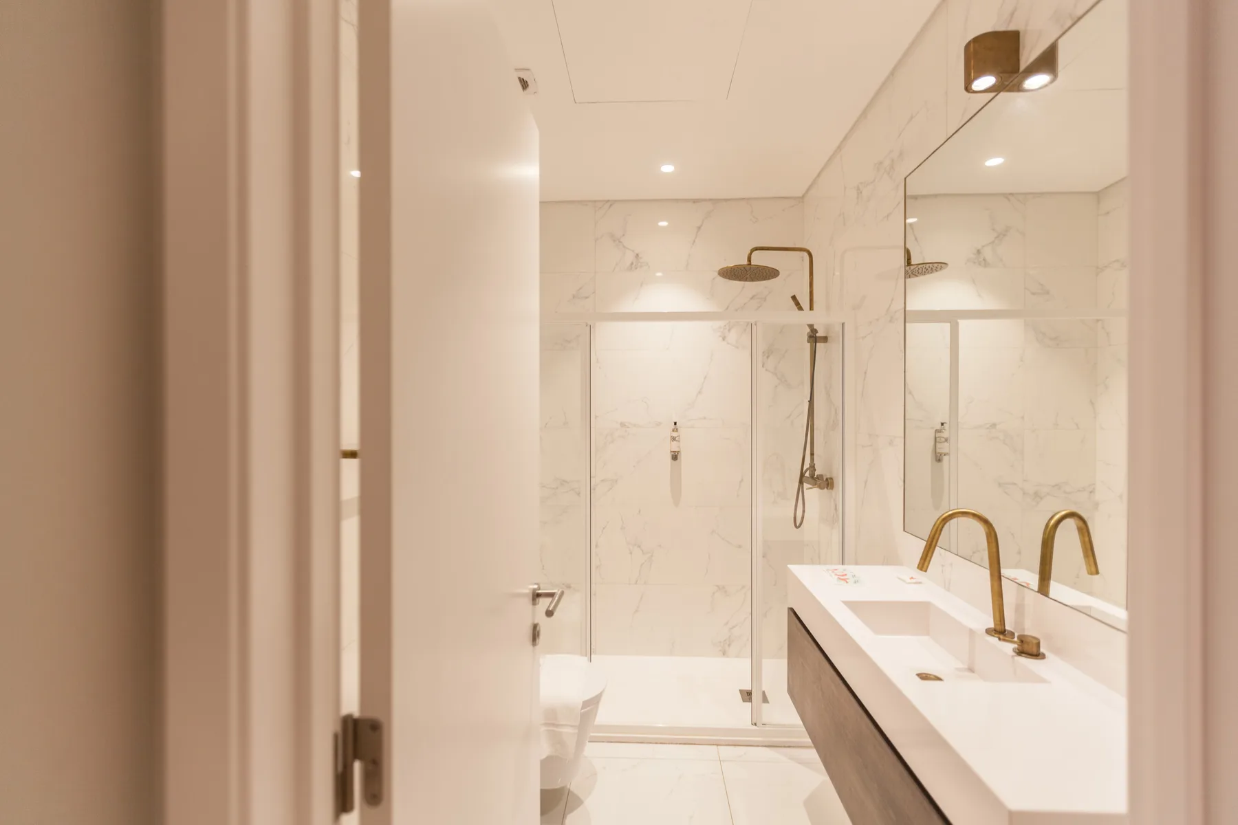 Un baño luminoso con ducha y una encimera larga con lavabo.