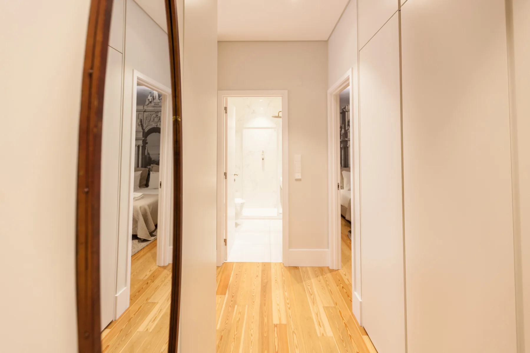 Un pasillo luminoso con suelo de madera y puertas de armario con espejo.