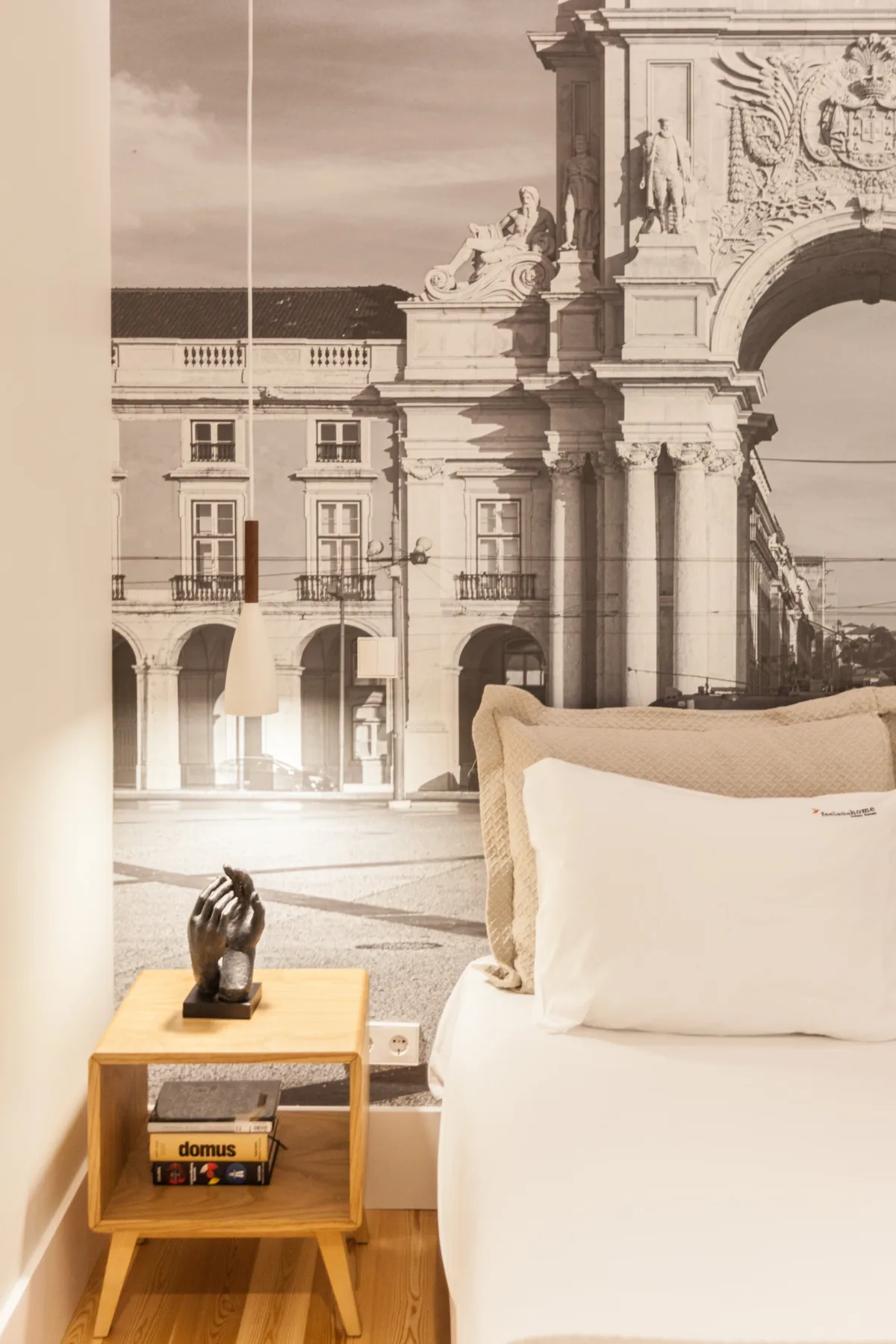 Un dormitorio con ropa de cama blanca junto a una gran imagen urbana en la pared.