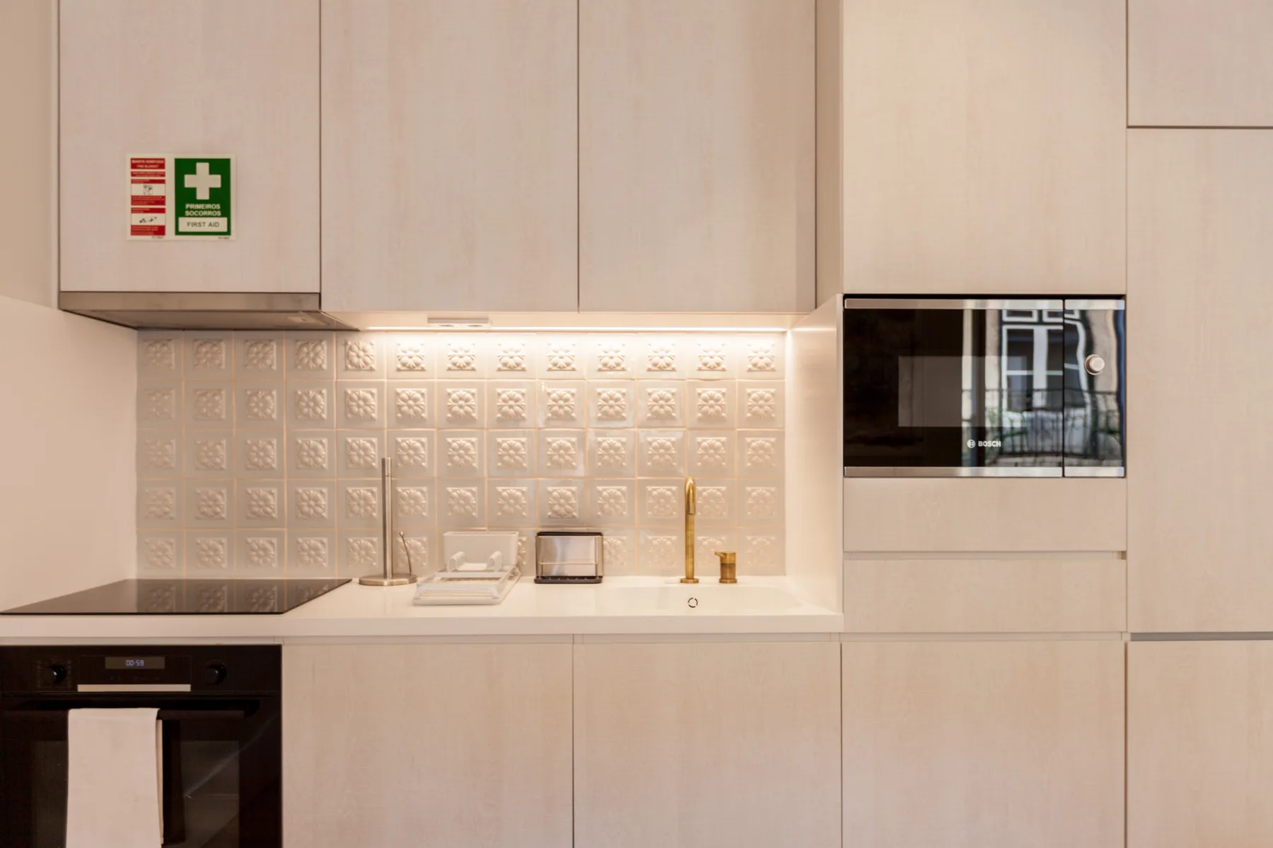 Una cocina moderna con armarios claros, horno y microondas integrado.