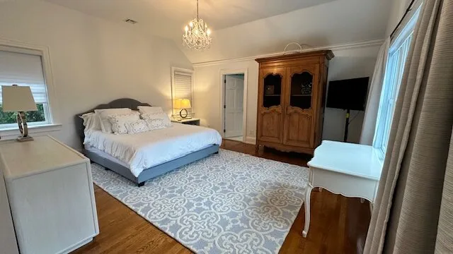 A bedroom with a bed, patterned rug, and wooden wardrobe.