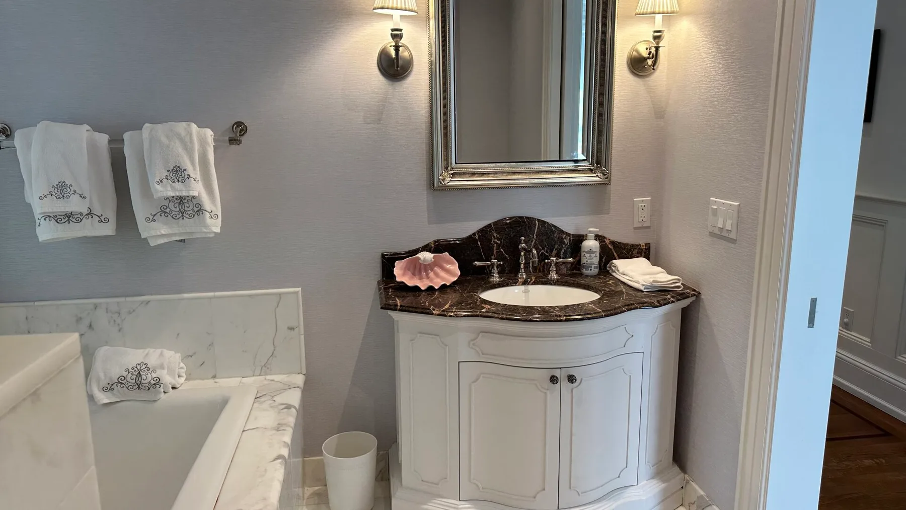 A bathroom vanity with a sink and mirror sits beside a bathtub.