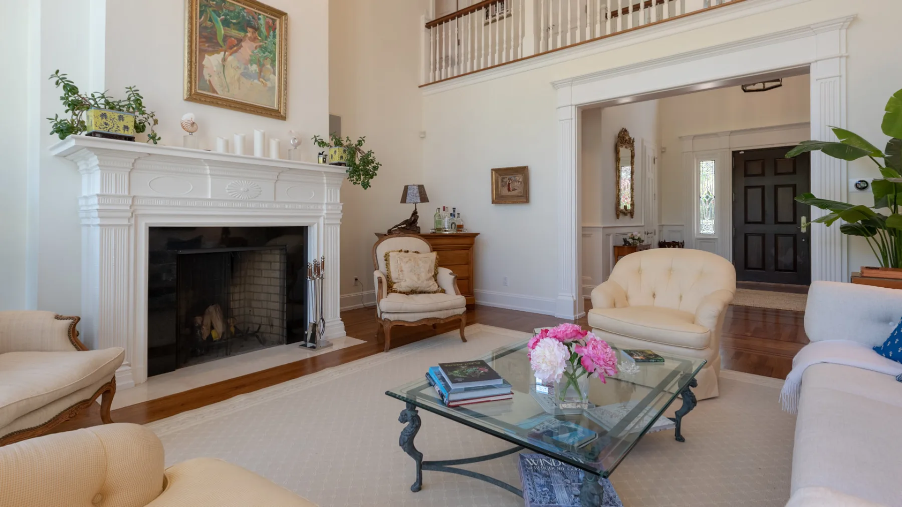 A bright living room with a fireplace, seating, and a glass coffee table.