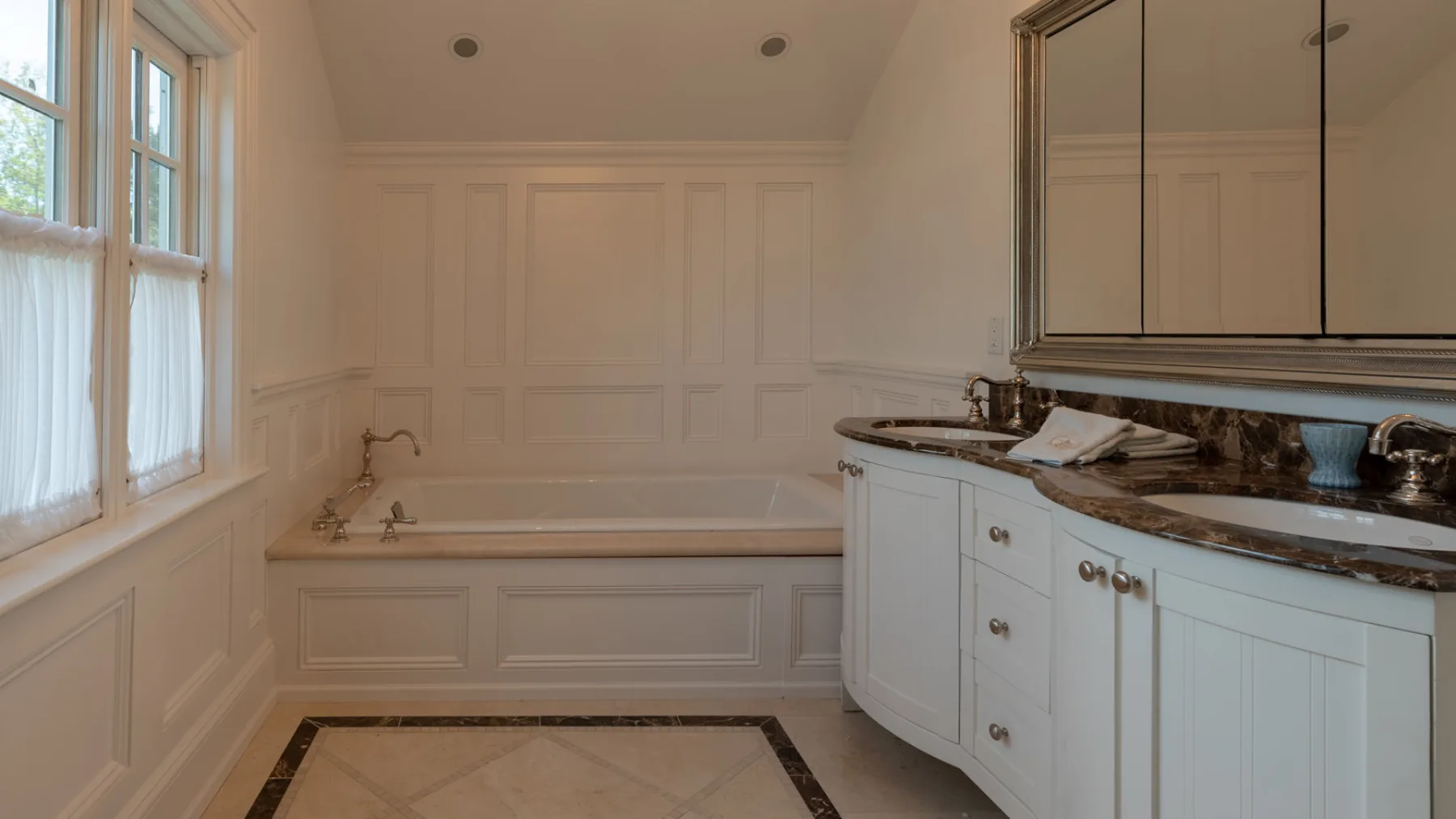A bright bathroom with a built-in bathtub and a long vanity.