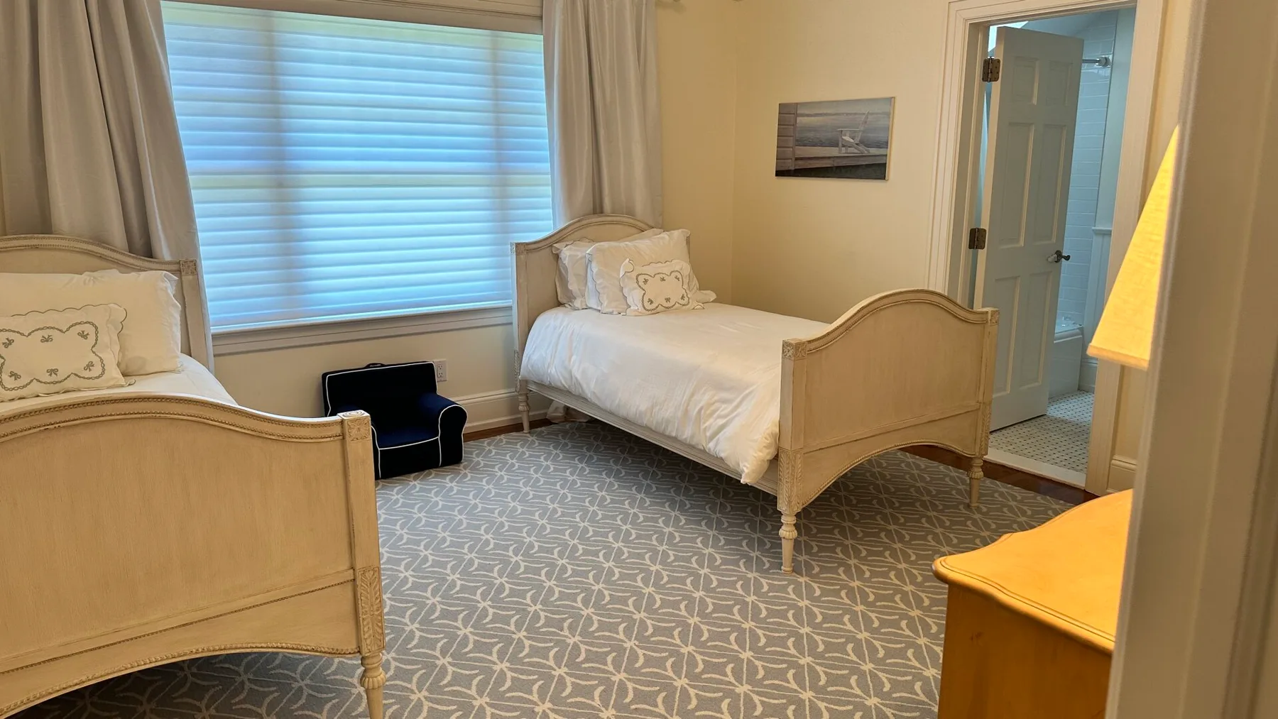 A bedroom with two beds, a large window, and patterned carpet.