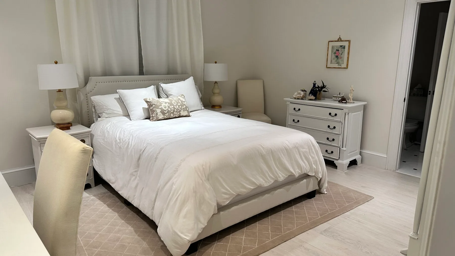 A bedroom with a neatly made bed, bedside tables, and a dresser.